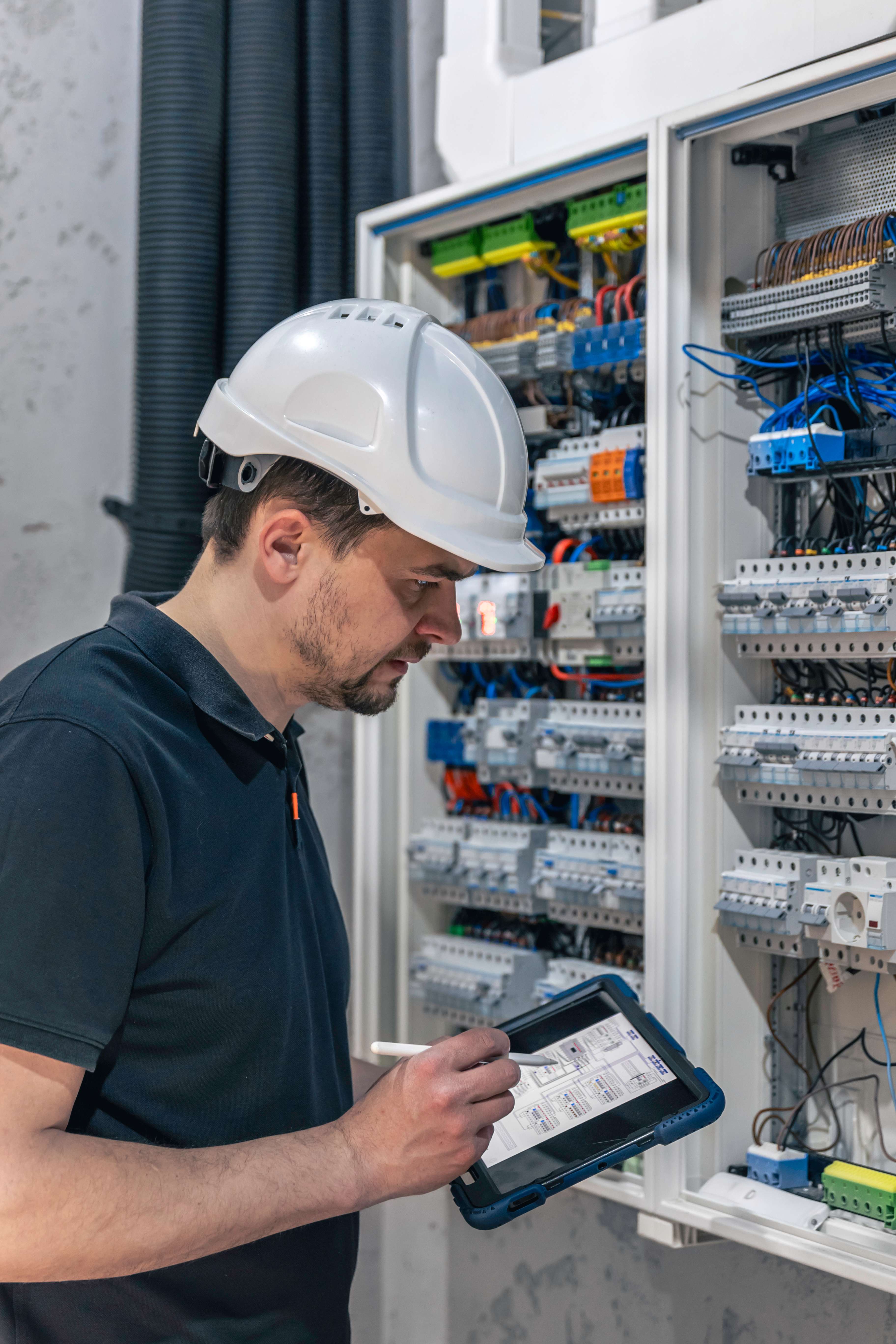 Elektrotechnik Elektro Beskydy kontroluje schéma na tabletu u rozvaděče s jističi